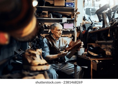 Elderly craftsman inspecting a handcrafted shoe in his traditional workshop - Powered by Shutterstock