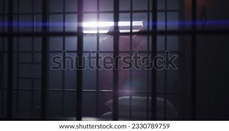 Elderly criminal in orange uniform sits in jail cell, stands up and looks on window with bars. Guilty inmate in detention center or correctional facility. Prisoner serves imprisonment term.