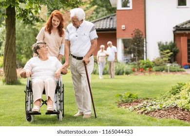 An elderly disabled couple with their caretaker in the garden outside of a private rehabilitation clinic. - Powered by Shutterstock