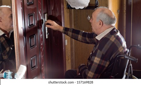 Elderly disabled man in a wheelchair checking the locks on the front door of the house to ensure he is safe and secure - Powered by Shutterstock