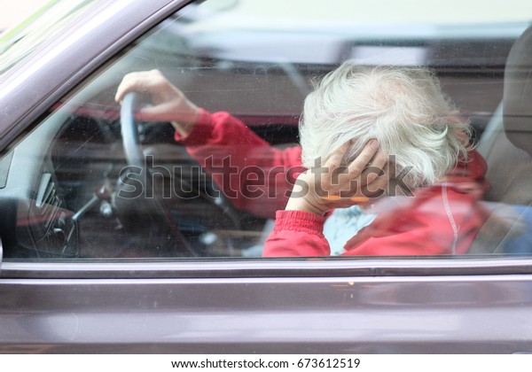 The elderly driver of the car resting sitting\
behind the wheel