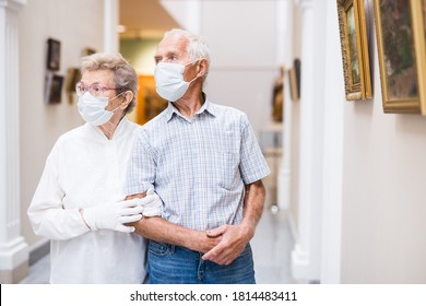 Elderly European Couple In Mask Protecting Against Covid Examines Paintings On Display In Hall Of Art Museum