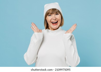 Elderly Excited Cheerful Happy Fun Satisfied Grandmother Caucasian Woman 50s In White Knitted Sweater Hat Spread Hands Isolated On Plain Blue Color Background Studio Portrait. People Lifestyle Concept