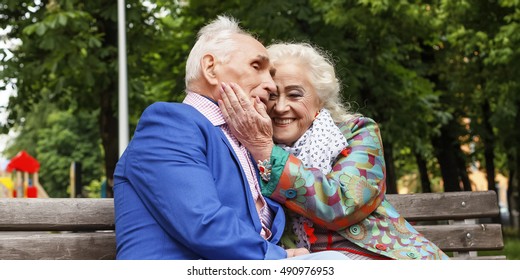 Elderly family couple talking on a bench in a city park. Happy seniors dating