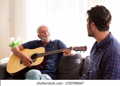 Elderly father playing guitar on the sofa at home and Adult Son sing a song. Family relations and stay at home - Powered by Shutterstock