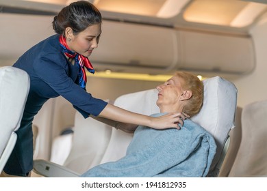 The elderly female passenger was sleeping, the flight attendant covered her blanket with a blanket to provide good care for the passengers on the plane. 