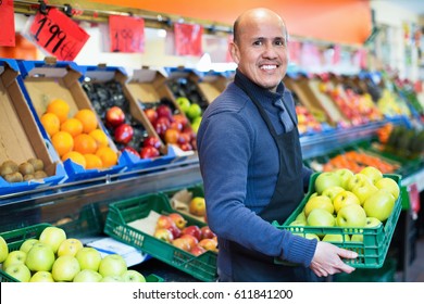 Elderly friendly  positive seller offering seasonal ripe fruits in local grocery - Powered by Shutterstock