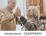 Elderly friends dancing happily indoors. Smiling seniors enjoying a dance. Joyful elderly pair sharing a moment. Senior friends embracing dance and happiness. Happiness and joy at old age.