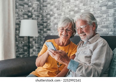 Elderly grandfather and grandmother spend time having fun using smartphone apps, middle-aged wife enjoy online entertainments, taking selfie with old husband, older generation and modern tech concept - Powered by Shutterstock