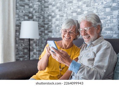 Elderly grandfather and grandmother spend time having fun using smartphone apps, middle-aged wife enjoy online entertainments, taking selfie with old husband, older generation and modern tech concept - Powered by Shutterstock