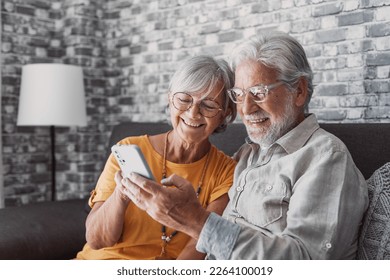 Elderly grandfather and grandmother spend time having fun using smartphone apps, middle-aged wife enjoy online entertainments, taking selfie with old husband, older generation and modern tech concept - Shutterstock ID 2264100019