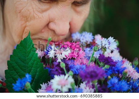 Elderly grandmother with a bouquet of flowers in the park