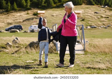 Elderly grandmother and her grandchild share a leisurely stroll through nature, enveloped in the beauty of their surroundings, fostering a bond that transcends generations - Powered by Shutterstock