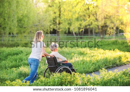 Similar – Woman carrying her mother in a wheelchair