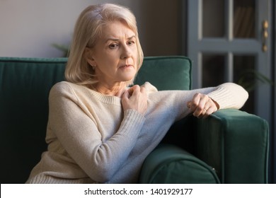 Elderly grey-haired pensive depressed woman sit on sofa alone at home lost on sad thoughts, grandmother thinking about problems difficulties, having senile diseases, mental emotional disorders concept - Powered by Shutterstock