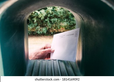 An Elderly Hand Holding A Vote By Mail Envelope In A Mailbox