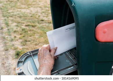 An Elderly Hand Holding A Vote By Mail Envelope In A Mailbox