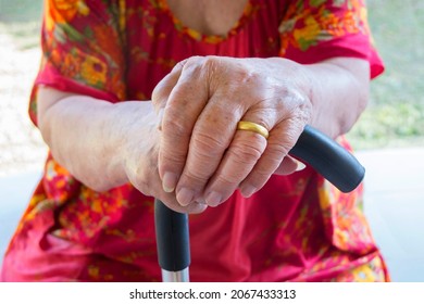 Elderly hand holding a walking cane , Asian old woman standing with  hands on a walking stick