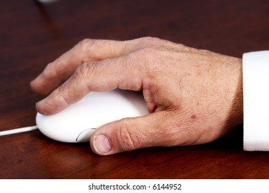 Elderly Hand Using A Computer Mouse On A Desk