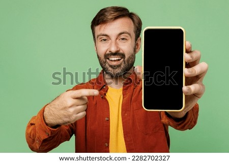 Elderly happy man 40s years old he wears casual clothes red shirt t-shirt hold use point on close up mobile cell phone with blank screen workspace area isolated on plain pastel light green background