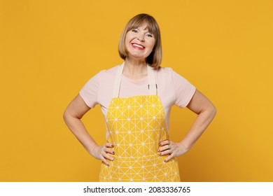 Elderly happy smiling fun housekeeper housewife woman 50s wearing orange apron standing akimbo arms on waist isolated plain on yellow background studio portrait. People household lifestyle concept. - Powered by Shutterstock