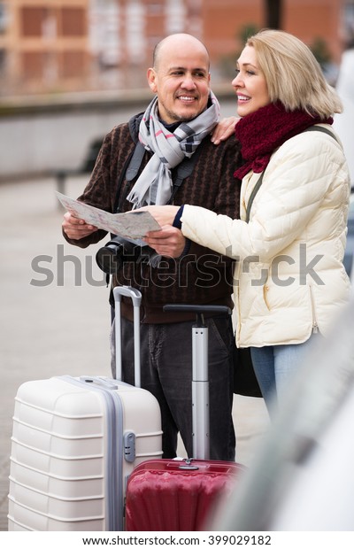 Elderly\
happy spouses with baggage and paper map\
outdoors