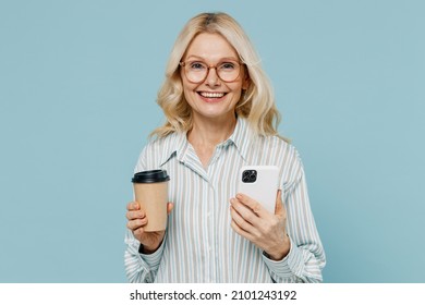 Elderly happy woman 50s in striped shirt glasses hold takeaway delivery craft paper brown cup coffee to go use mobile cell phone isolated on plain pastel light blue color background studio portrait. - Powered by Shutterstock