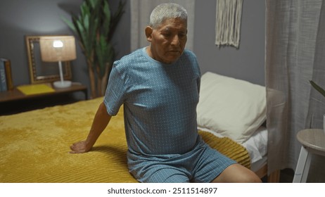 Elderly hispanic man with grey hair sitting on a bed in a cozy bedroom at home, wearing pajamas, and looking thoughtful. - Powered by Shutterstock