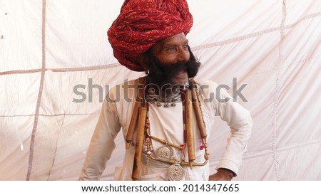 An elderly Indian man in traditional clothes and turban on his head happily talking