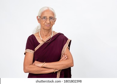 Elderly Indian Woman Wearing Spectacles Stands With Her Arms Folded. Senior Woman With A Serious Expression Looking Into The Camera