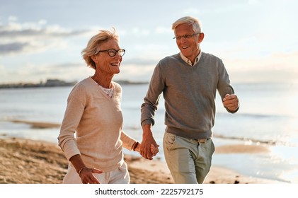 Elderly intelligent couple in love spending time romantically on the beach near the sea, walking holding hands and gently hugging. - Powered by Shutterstock