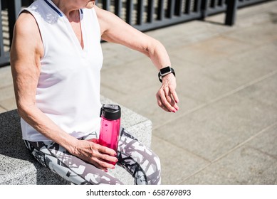 Elderly lady checking up time of rest outside stadium building - Powered by Shutterstock