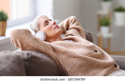 Elderly lady in headphones lying on couch and listening to music with closed eyes while resting in cozy living room at home
 - Powered by Shutterstock