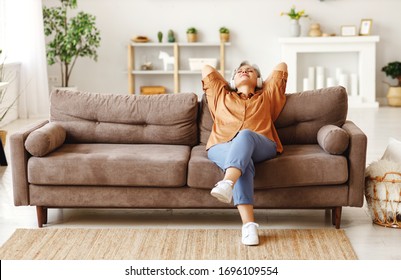 Elderly lady in headphones sitting on couch and listening to music with closed eyes while resting in cozy living room at home
 - Powered by Shutterstock