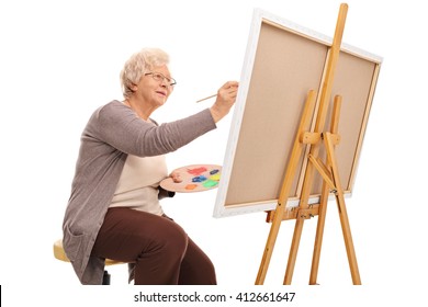 Elderly Lady Painting On A Canvas With A Paintbrush Isolated On White Background