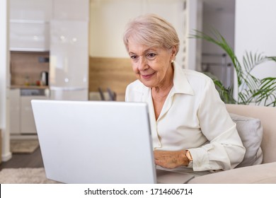 Elderly Lady Working With Laptop. Portrait Of Beautiful Older Woman Working Laptop Computer Indoors. Senior Woman Using Laptop At Home, Laughing