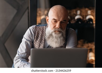 Elderly Liquor Store Owner Works On A Laptop .