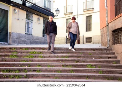 Elderly Male And Female Couple Walking Down Stairs On A Stroll