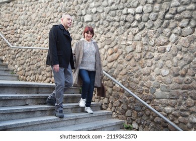 Elderly Male And Female Couple Walking Down Stairs On A Stroll