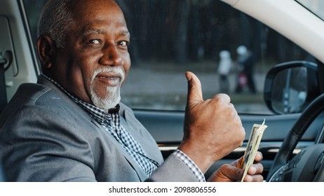 Elderly male sitting in car counting cash payment wages mature african american businessman calculates income successful business happy smiling man looking at camera shows thumbs up gesture approval - Powered by Shutterstock