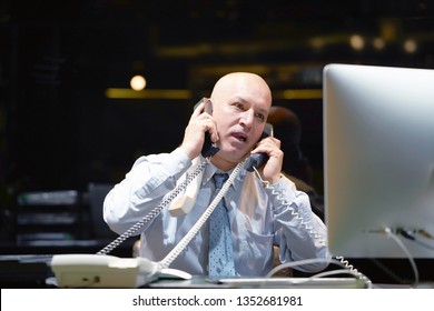 Elderly Male Social Worker Swear On The Phone. Close-up Of An Call Center Worker. Elderly Man Secretary Hospital Answering Phone Calls And Swear With Customers. A Lot Of Phone Calls.