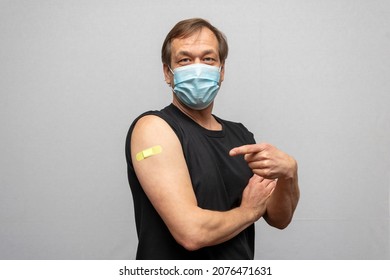 An elderly man of 45-50 years old wearing a medical mask points to a dressing with the COVID-19 vaccine as part of the coronavirus vaccination program.