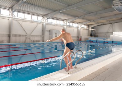 An elderly man is actively engaged in swimming and sports in the pool in a retired sports complex