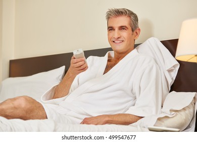 Elderly Man In Bathrobe Watching TV In A Hotel Room