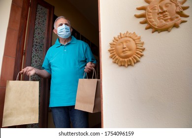 Elderly Man With Blue Polo And Face Mask, Leaves The House With Shopping Bags