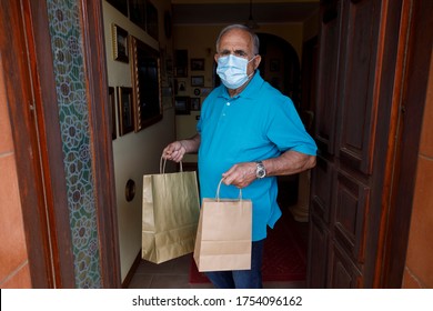 Elderly Man With Blue Polo And Face Mask, Leaves The House With Shopping Bags