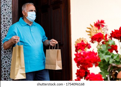 Elderly Man With Blue Polo And Face Mask, Leaves The House With Shopping Bags