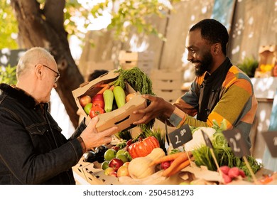 Elderly man buying various seasonal fruits and vegetables at farmers market during autumn. Smiling African American vendor offering homegrown organic sustainable produce to senior customer. - Powered by Shutterstock