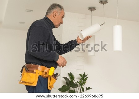 Elderly man changing light bulbs : Retired man doing household chores, replacing the light bulbs and domes, skillfully decorated.