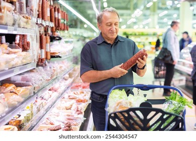 Elderly man chooses sausage in supermarket - Powered by Shutterstock